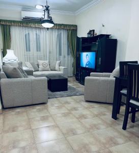 uma sala de estar com sofás e uma televisão de ecrã plano em Karnak Flats em Luxor