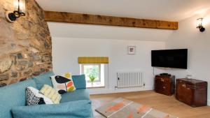 a living room with a blue couch and a flat screen tv at Pipistrelle Barn in Kniveton