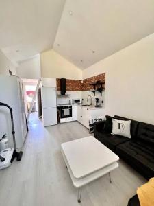 ein Wohnzimmer mit einem schwarzen Sofa und einem weißen Tisch in der Unterkunft Attefallshus Alingsås / Dammen. in Alingsås