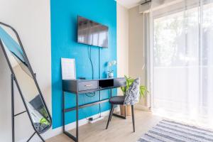 Habitación con escritorio y TV en una pared azul. en Studio GDX Privilége - Bourg en Bresse - Centre ville & Gare en Bourg-en-Bresse