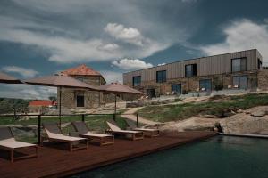 a pool with chairs and umbrellas next to a building at Bode Country House in Monsanto