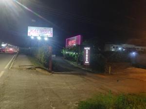 una calle vacía por la noche con letreros de neón en Motel Kalipso en São José