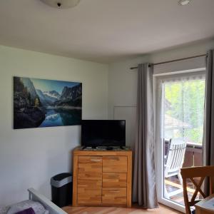 uma sala de estar com televisão numa cómoda de madeira em Gästehaus Lehnerer Grainau em Grainau