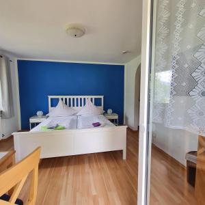 um quarto com uma cama branca e uma parede azul em Gästehaus Lehnerer Grainau em Grainau