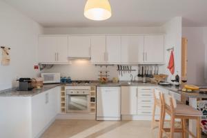 a kitchen with white cabinets and white appliances at H2Ome by An Island Apart in Porto Santo