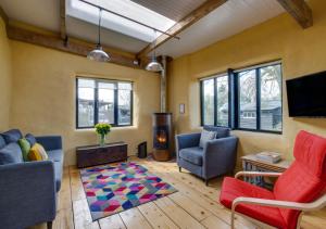 uma sala de estar com um sofá e cadeiras e uma lareira em Straw Bale Cottage em Haughley