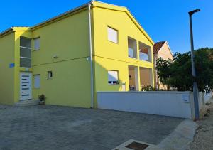 un edificio amarillo y verde junto a una calle en Mala Smokva en Vir