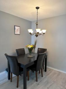 a dining room table with black chairs and a chandelier at CastleRooms Homestay in Ottawa