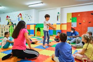 a group of children sitting on the floor in a room at Family Hotel Andes - Only for Family in Vigo di Fassa