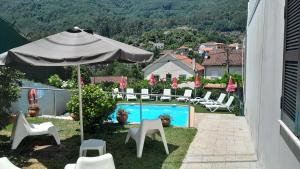 a patio with an umbrella and chairs and a pool at Serrana Gerês in Geres