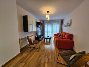 sala de estar con sofá rojo y sillas en 13B01 Apartamento con terraza y garaje, en Ribadesella