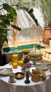 una mesa con alimentos para el desayuno y zumo de naranja en ella en Riad Dar Zaman en Marrakech