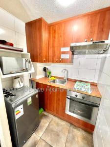a small kitchen with wooden cabinets and a sink at Acuña & Donoso Apartamentos Centro in Santiago