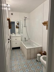 a bathroom with a tub and a sink and a toilet at Bel appartement 8 personnes à Saint Chaffrey in Saint-Chaffrey
