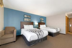 a hotel room with two beds and a chair at Sleep Inn & Suites Hays I-70 in Hays