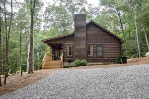 une cabane en rondins dans les bois avec une allée en gravier dans l'établissement Fishful Thinking, à Cherry Log