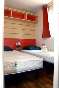 two beds in a room with a teddy bear sitting on them at Mobilhome «Perle marine»*6 personnes *3 Chambres*TV in Sigean