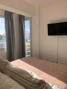 a bedroom with a bed and a flat screen tv at Depto Caleta Madryn in Puerto Madryn
