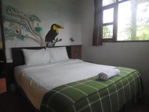 1 dormitorio con 1 cama con un pájaro en la pared en Biohostal Mindo Cloud Forest, en Mindo