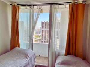 a bedroom with a window with a view of a city at Acuña & Donoso Apartamentos Centro in Santiago