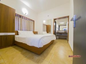 a bedroom with a large bed and a bathroom at Vue D'en Haut, Ooty in Ooty