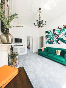 ein Wohnzimmer mit einem grünen Sofa und einem Kronleuchter in der Unterkunft New Marylebone Gem/One Bedroom in London