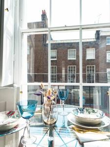 einen Glastisch mit Tellern und Gläsern an einem Fenster in der Unterkunft New Marylebone Gem/One Bedroom in London