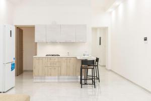 eine Küche mit weißen Schränken, einer Theke und Stühlen in der Unterkunft La Suite Cagliari - Cagliari centro in Cagliari
