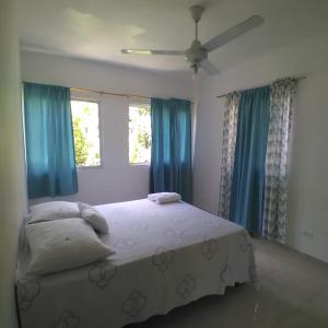 a bedroom with a large bed with blue curtains at Aparta Hotel Ana Luis in Río San Juan