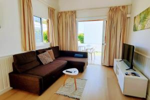 a living room with a brown couch and a television at Precioso Bungalow 12 in Playa del Ingles