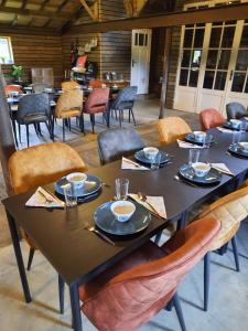 uma sala de jantar com mesa e cadeiras com pratos em Landgoed Julianahoeve em Helenaveen