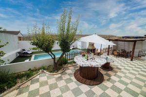 een patio met een tafel, een parasol en een zwembad bij Magnificent villa: 2 private pools, BBQ, garden & parking. 13 per. In Padul in Granada