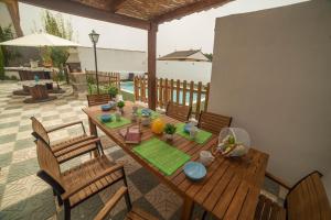 een houten tafel en stoelen op een patio bij Magnificent villa: 2 private pools, BBQ, garden & parking. 13 per. In Padul in Granada