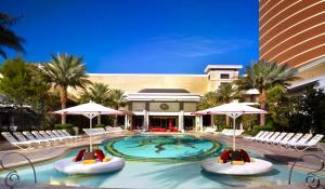 einen Pool mit Stühlen und Sonnenschirmen in einem Resort in der Unterkunft Encore at Wynn Las Vegas in Las Vegas