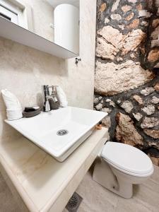 La salle de bains est pourvue d'un lavabo et de toilettes. dans l'établissement Harmonia Bungalows & Pool, à Sveti Stefan