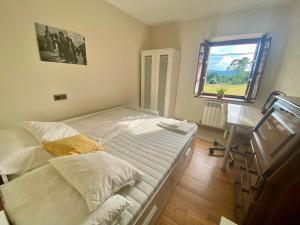 1 dormitorio con cama, escritorio y ventana en Villa Paraes en Nava