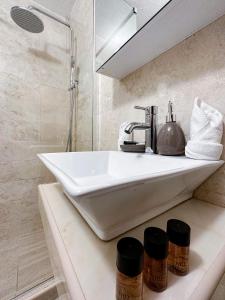 ein Badezimmer mit einem weißen Waschbecken und einer Dusche in der Unterkunft Harmonia Bungalows & Pool in Sveti Stefan