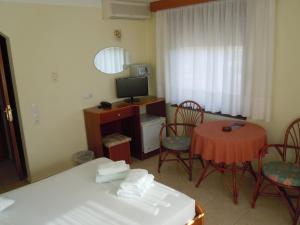 a room with a bed and a desk with a television at Tropicana in Paralia Katerinis