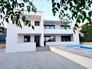 a white house with a swimming pool in front of it at Villa Leptirić in Vir