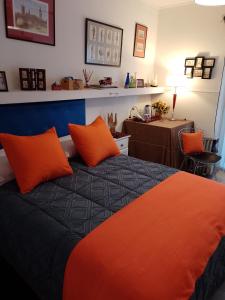 um quarto com uma cama com almofadas laranja e uma secretária em B&B - El Refugio -C D em Paraná