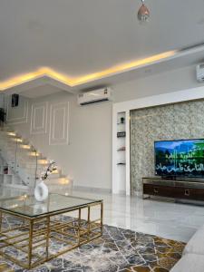 ein Wohnzimmer mit einem Glastisch und einem TV in der Unterkunft Sky ittin سما إتين in Salalah