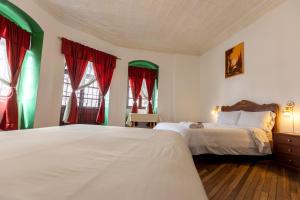 a bedroom with two beds and two windows at Vibes Aurik in Quito