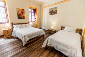 a bedroom with two beds and two windows at Vibes Aurik in Quito