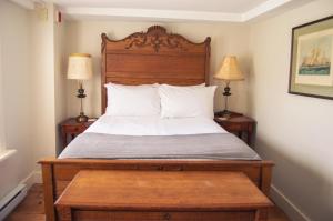 a bedroom with a bed with a wooden headboard and two lamps at The General Stanton Inn in Charlestown