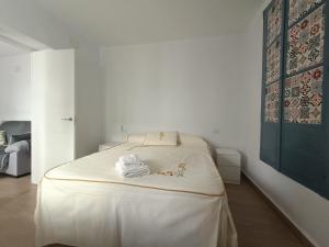 a white bedroom with a large bed with white sheets at El barrio in Medina Sidonia