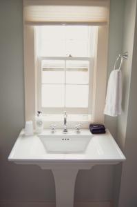 a white sink in a bathroom with a window at The General Stanton Inn in Charlestown