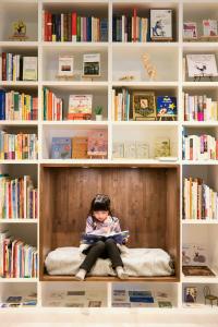 a little girl sitting on a shelf reading a book at Tornare Gakuenmae #105 - Vacation STAY 14291 in Nara