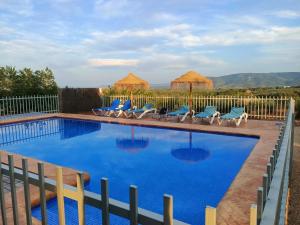 a swimming pool with blue chairs and a fence at Casa Rural la Montana 2 in Chella