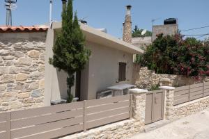 una casa con una valla y una pared de piedra en Faistos Cottage, en Áyios Ioánnis