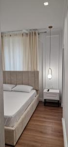 a bedroom with a large white bed and a lamp at Heart of Tirana Apartment in Tirana